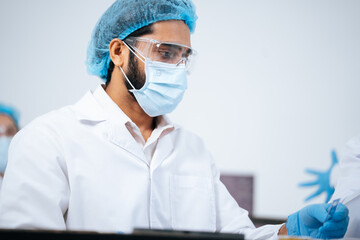 Fototapeta premium Scientist analyzing virus data to find a new antiviral medicine, wearing protective PPE gear in a sterile laboratory during a dangerous virus outbreak research