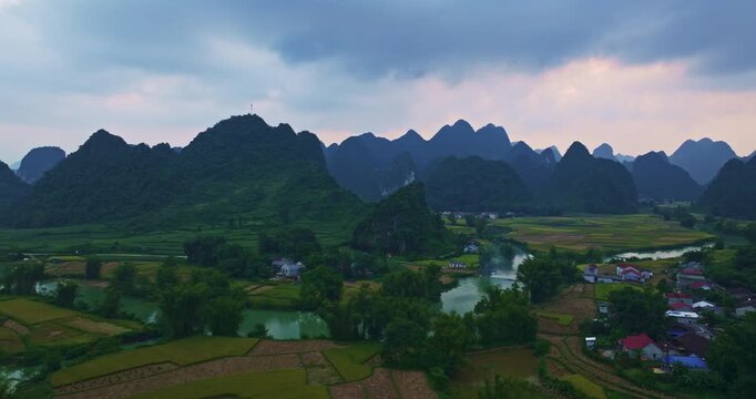 Aerial View of Misty Valley River Landscape. Scenic countryside panorama with layered limestone peaks, reflective waterways, and vibrant farmland creating a tranquil and atmospheric natural setting.