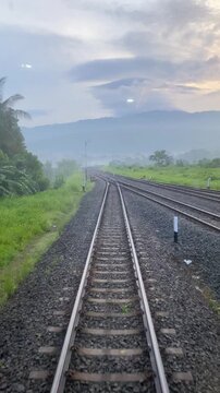 Cinematic View of Train Tracks Vanishing into Misty Mountains at Dawn