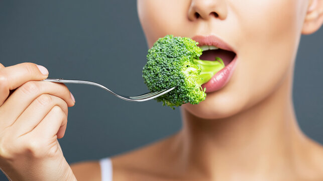 Woman bringing vibrant green broccoli to her mouth with a fork, representing a clean eating lifestyle and wholesome nutrition