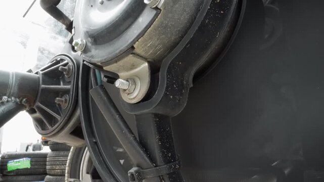 Closeup brake drum axle assembly detail showing hub, hose and bracket workshop atmosphere with grease speckles, metal texture, mounting bolts and linkage, technician service context, precise
