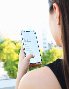 Mujer observando saludo de chatbot de inteligencia artificial en pantalla de inicio de su tel&eacute;fono inteligente