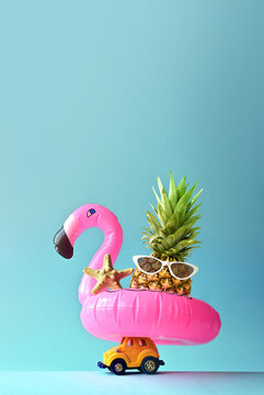 Pink inflatable flamingo on toy car and pineapple. Summer pool float party idea. Summer concept.