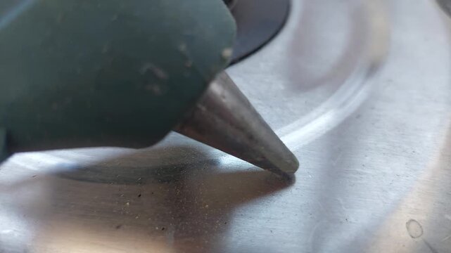 Close up of hot glue gun nozzle on metal surface