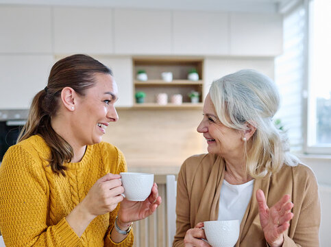 Portrait of mother and daughter  having fun, chating drinking coffee, sitting and hugging  at home, family life, parenting, love and bonding concepts