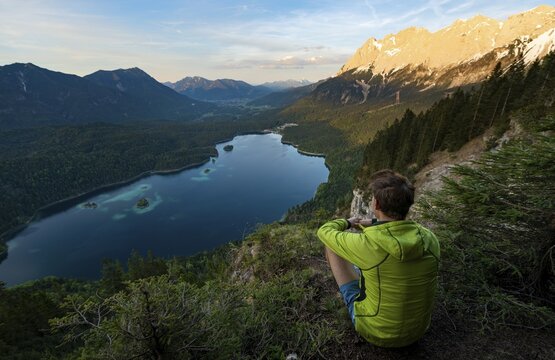 Young man looking over the Eibsee lake at sunset, Zugspitze and Zugspitzmassiv, alpenglow, behind Bishop and Krottenkopf, Wetterstein Mountains, near Grainau, Upper Bavaria, Bavaria, Germany