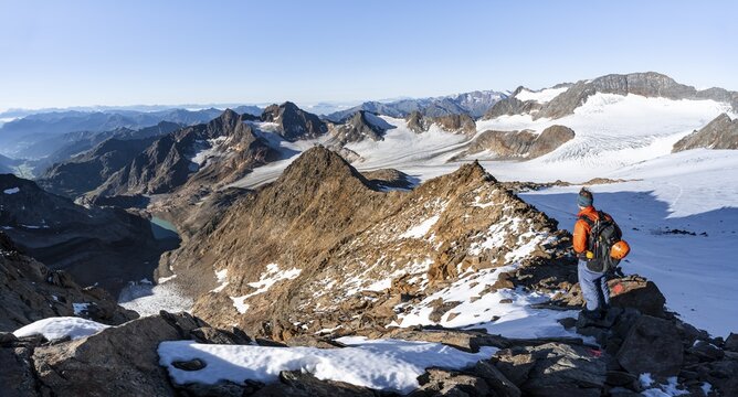 Mountaineer on a rocky ridge on the Wilder Freiger summit, behind him Signal summit and Becher summit with Becherhaus, picturesque high mountain landscape, view of &Uuml;beltalferner glacier and rocky mountain peaks K&ouml;nigshofspitz and Sonklarspitze, Stubai Alps, South Tyrol, Italy