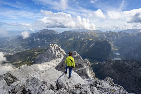Mountaineer on the rocky summit of the Watzmann Mittelspitze, Watzmann crossing, view of mountain panorama with Steinernes Meer and K&ouml;nigssee, Kleiner Watzmann and Watzmann children, Berchtesgaden National Park, Berchtesgaden Alps, Bavaria, Germany
