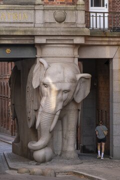 Pedestrian walking past monumental stone elephant, Elephant Gate or Elephant Portal or Elefantporten, by architect Vilhelm Dahlerup, Carlsberg district, Copenhagen, Denmark