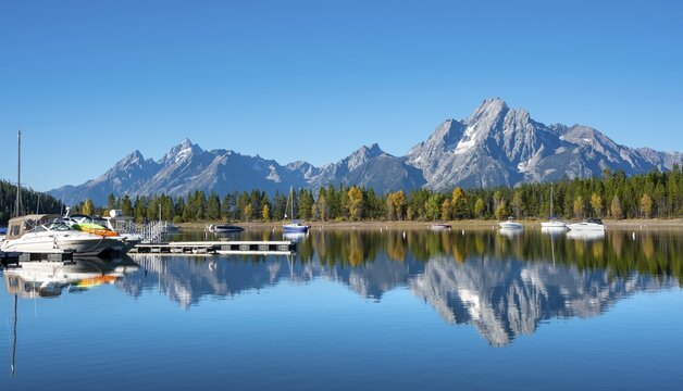 Mountains reflected in the lake, Jackson Lake, sailboats and motorboats in a bay, Colter Bay in autumn, Teton Range mountain range, Grand Teton National Park, Wyoming, USA