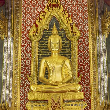Golden meditating Buddha surrounded by wall paintings with Buddhist teachings and representations of Buddha's disciples, Wat Makut Kasatriyaram Ratchaworavihan, Phra Nakhon District, Old Bangkok, Thailand