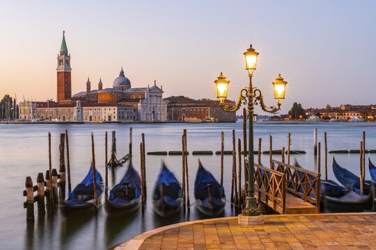 Venetian gondolas at St. Mark's Square in the evening light, blue hour, in the back monastery San Giorgio Maggiore, district San Marco, Venice, region Veneto, Italy