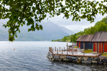 Slow everyday life by Hardangerfjord with traditional wooden cabins by the water in Lofthus,low clouds across the mountains of western Norway. Local travel and quiet Nordic atmosphere themes. © Nimbus Works