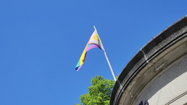 Intersex Inclusive Progress Pride Flag against a blue sky on top of a building in a european country. 