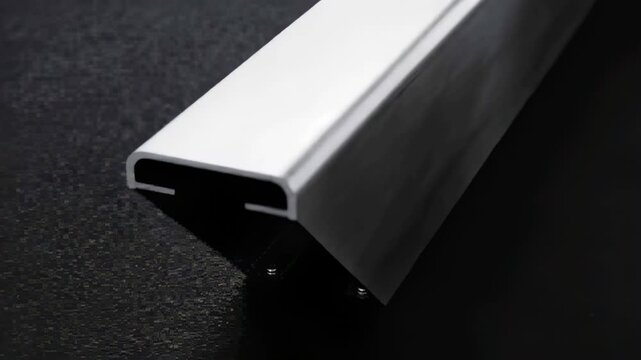 Rotating camera revealing aluminum extrusion diagonally on dark mat, exposing clip and screws