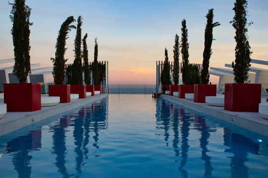 Sunset Reflected in Rooftop Infinity Pool hotel resort orange blue sky water swimming red reflection mirror image photo photograph editorial luxury trees plants symmetrical landscape png travel clouds