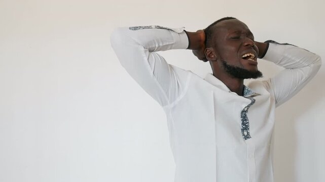 Humble prayer with gentle breathing. Man in white shirt prays calmly. Serene individual with hands on head prays softly. Tranquil scene of man praying with palms to face and hopeful expression