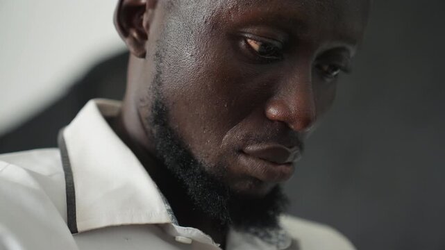 Close up weary man looking down, postshift fatigue in dim interior, subtle beard and collar, perspiration on forehead, cinematic grain, silent reflection, shallow focus, moody shadows, tired