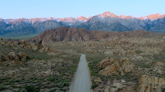 Alabama Hills California - Approach Over Road Towards Mt Whitney at Sunrise with Red Glow on Mountain Tops 