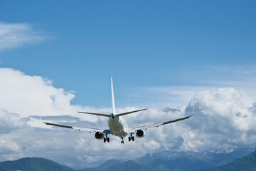 Fototapeta premium White aircraft on final approach against a blue sky with light clouds