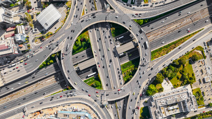 Urban infrastructure capturing the intricate network of roads, flyovers, and intense vehicle traffic flowing through a modern city roundabout and complex multi-level highway interchange © Nasos Zovoilis