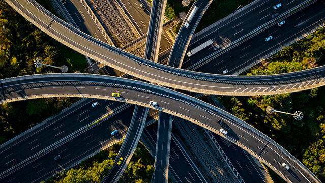 Aerial view of a major highway interchange featuring multiple layered roads and moving vehicles, symbolizing modern transportation networks, urban development, and intricate logistical connections