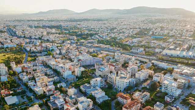 Marousi, athens cityscape establishing a wide residential and commercial urban sprawl, featuring numerous buildings, roads, and green spaces under a clear sunny sky with distant mountains