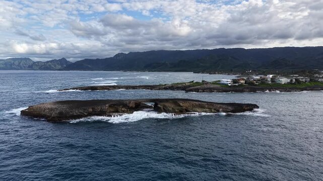 Close up view of the rock arch off Laie Point with the Koolau mountain range in the background in northeastern Oahu in Hawaii. 