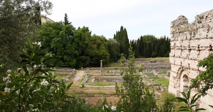 Ancient Roman ruins at Cimiez archaeological site in Nice with historic stone walls and columns. Mediterranean heritage park with antique masonry foundations and lush green cypress trees. Traditional