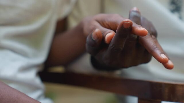 Black couple playful finger tracing during date, delicate fingertips, teasing touches, smiling tension, warm skin tones, wooden chair armrest, candid motion, chemistry and subtle flirtation.