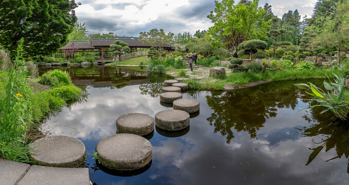 Nantes, France - 05 07 2026: Versailles Island garden. Panoramic view of water feature reflecting the Maison de l'Erdre, a replica of a traditional Japanese tea house and the Japanese garden in spring