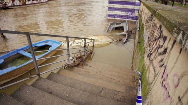 Flooded Pisuerga River overflowing pedestrian walkway in Valladolid, Spain.