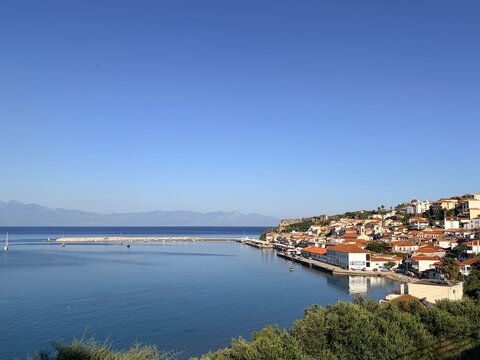 Koroni Greece, Mediterranean coastal town with red roof houses and calm blue sea under clear sky