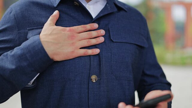 Person holds smartphone, hand placed over heart in sincere gesture. Conveys deep emotion, gratitude, and heartfelt feeling. Gesture indicates honesty, trust, and profound personal connection.