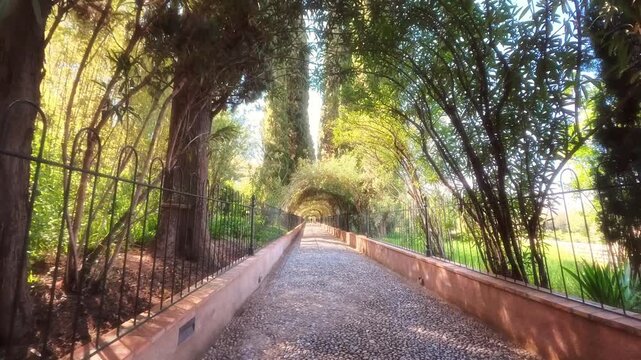 Peace full walk along Sunlit Garden Archway Pathway Through Green Arbor Tunnel With Dappled Shadows And Iron Fences, Alhambra, Spain