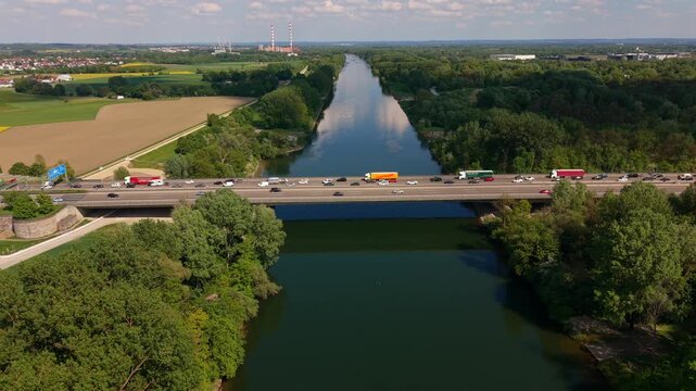 Aerial scene shows the A9 highway bridge over the Danube packed with slow moving vehicles. Road reconstruction creates a bottleneck as traffic crawls through the Ingolstadt area in sunny Bavaria.
