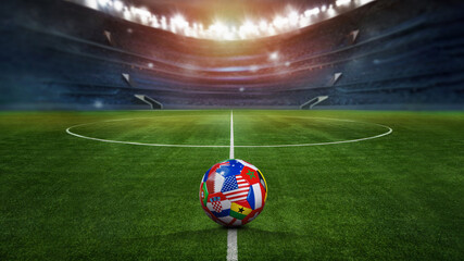 Fototapeta premium green textured field in soccer stadium and soccer ball covered with multiple national flags symbolizing an international football tournament. ready for game