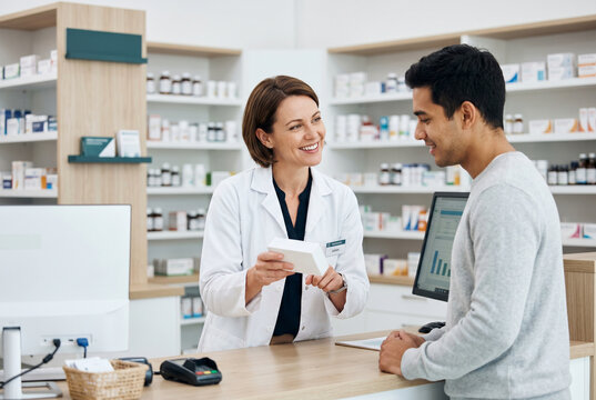 Professional female pharmacist explaining medication to a male customer at a pharmacy counter