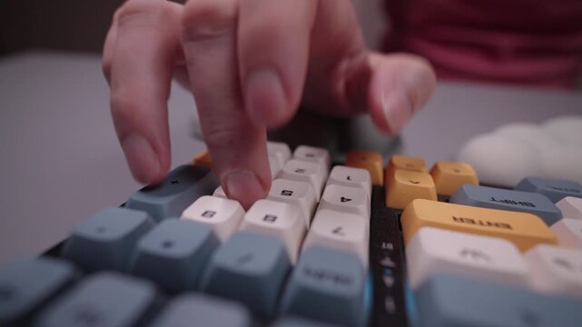Close-up of person hand typing on mechanical keyboard number pad, using supportive wrist rest to maintain ergonomic posture and prevent carpal tunnel syndrome.