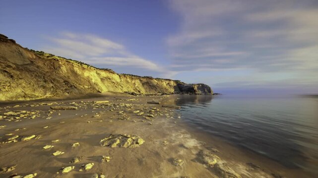 Pebblecovered coast at dawn with stratified cliffs. Sunrise illuminates pebblestrewn coast as expert examines geological stratification closely