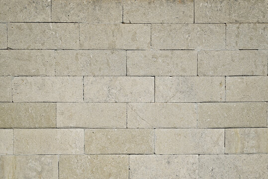 Beige stone brick wall made of rectangular limestone blocks. Neutral stone background for architecture, construction and design projects.
