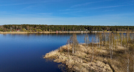 Obraz premium Aerial view of a lake with houses and forest on the shore