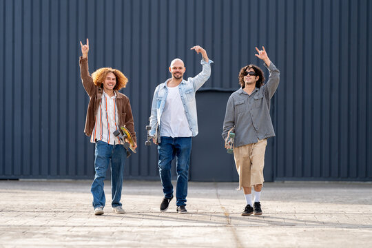 Friends skaters walking in urban street holding skateboards