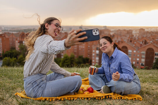 Two women friends taking a selfie at sunset in Madrid