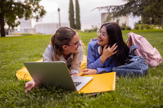 Female students studying with laptop and notes on campus