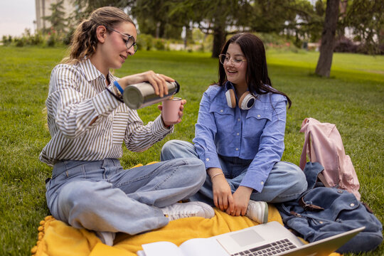 Women student friends relaxing on campus lawn picnic break