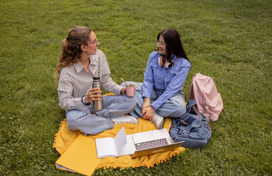 Female students sharing mate tea while studying outdoors