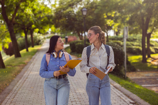 Two women students walking on campus path and chatting