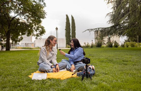 Female students filming a vlog on a university lawn