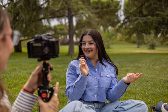 Female students filming a vlog on a college campus lawn